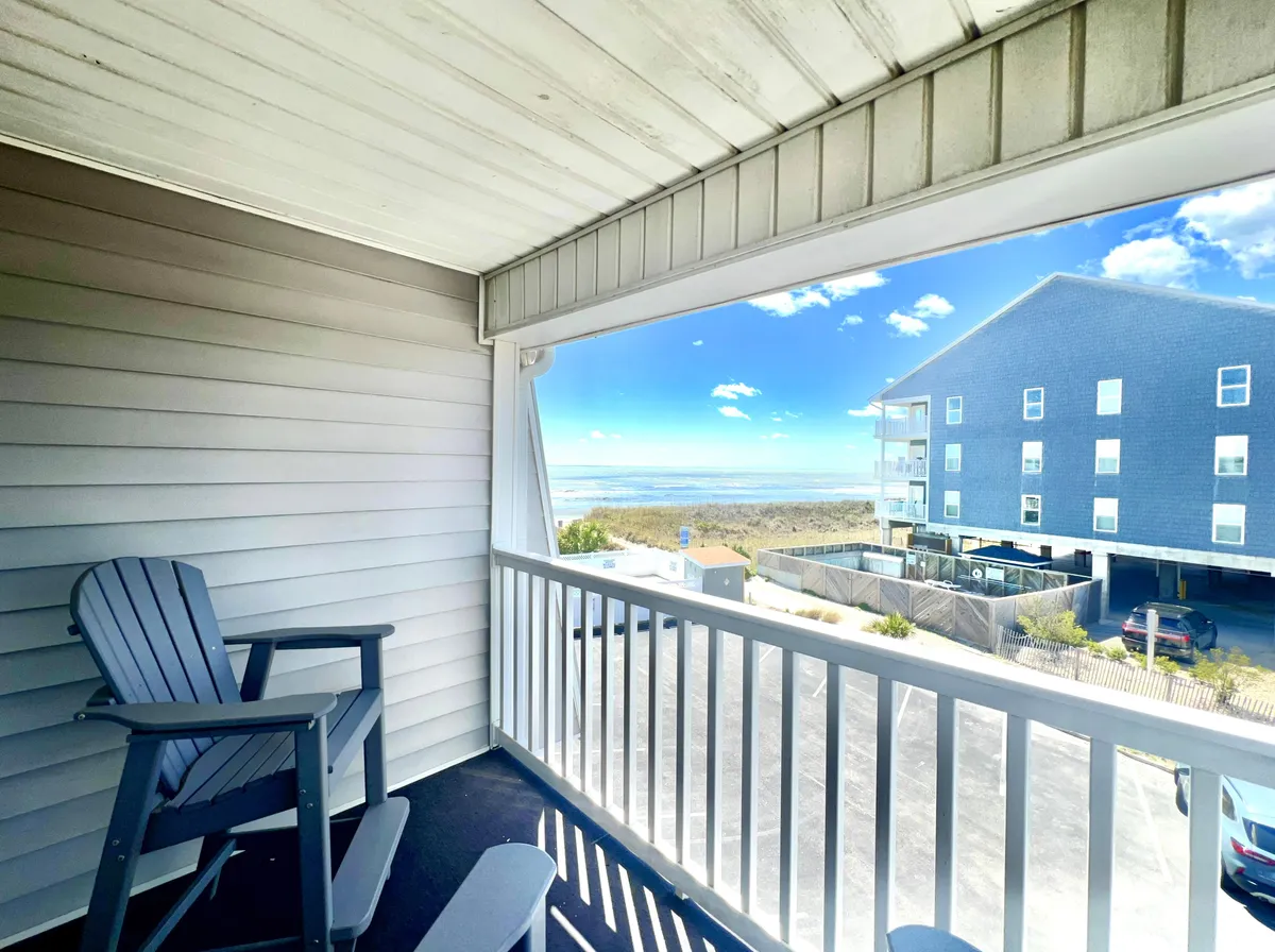 This exterior image showcases a private balcony overlooking the ocean, with an inviting Adirondack chair perfectly positioned to enjoy the tranquil view. The scene captures the essence of relaxation and leisure, with soft sunlight, calm waters, and a sense of privacy and exclusivity.
