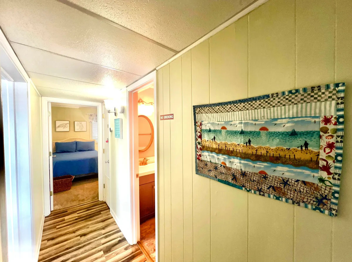 An inviting entryway with textured textile wall art and doorways leading to other rooms, setting a welcoming first impression. The scene hints at a relaxed and artful atmosphere, inspiring the sense of arrival and new experiences.